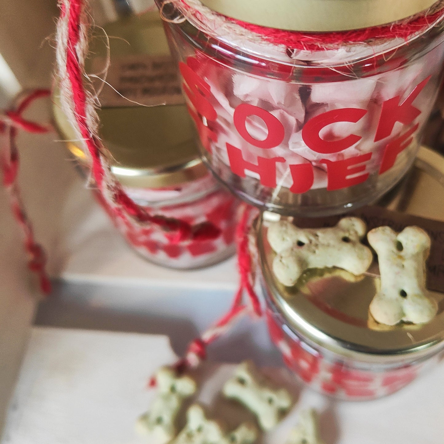 Stacked Jars labeled 'Sock Thief' with dog treats scattered on a white surface
