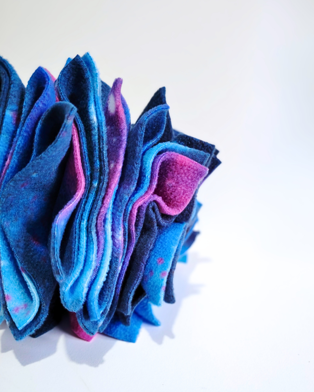 Folds of blue and pink fleece perfect to hide treats or kibble on a white background
