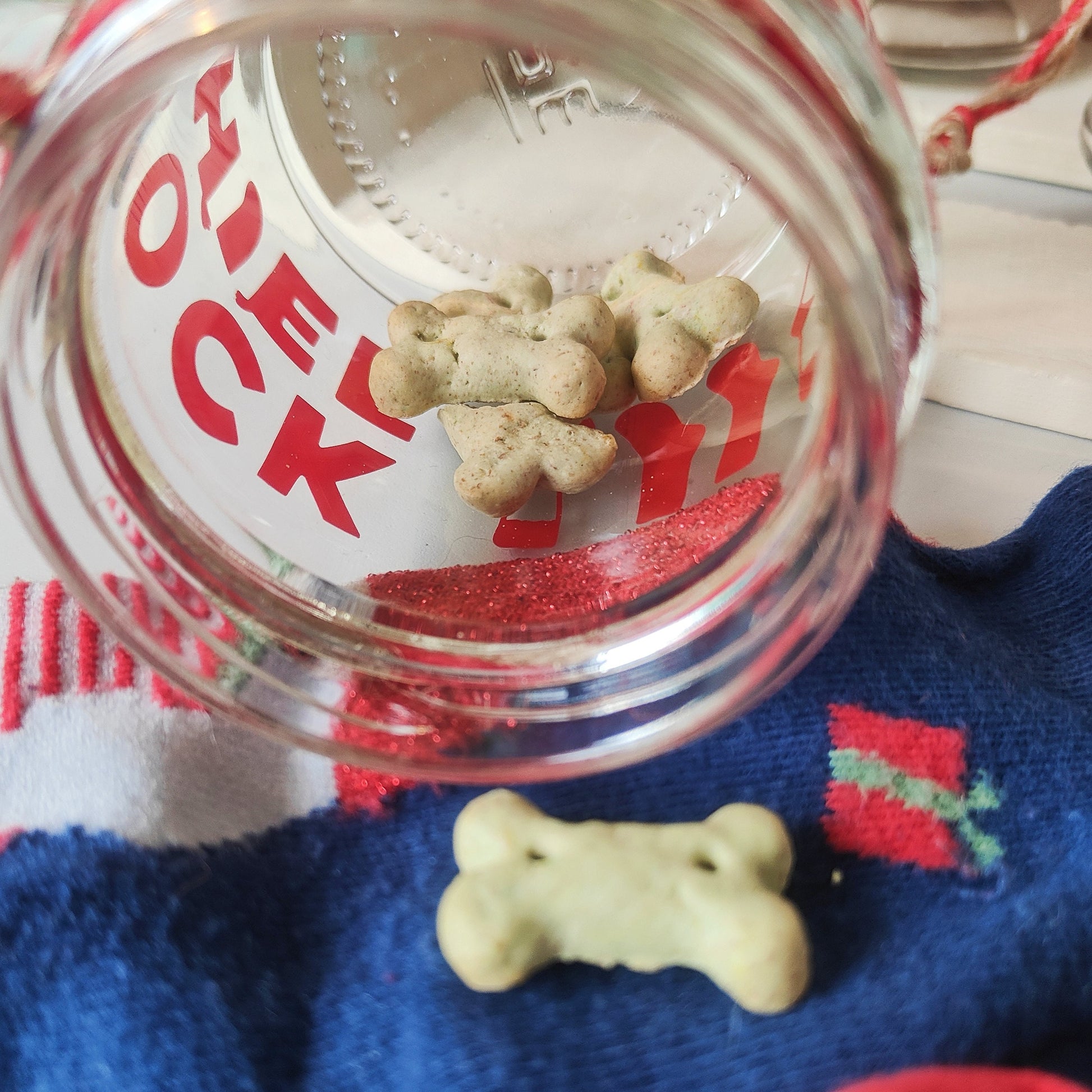 Clear glass jar with dog treats on a festive background