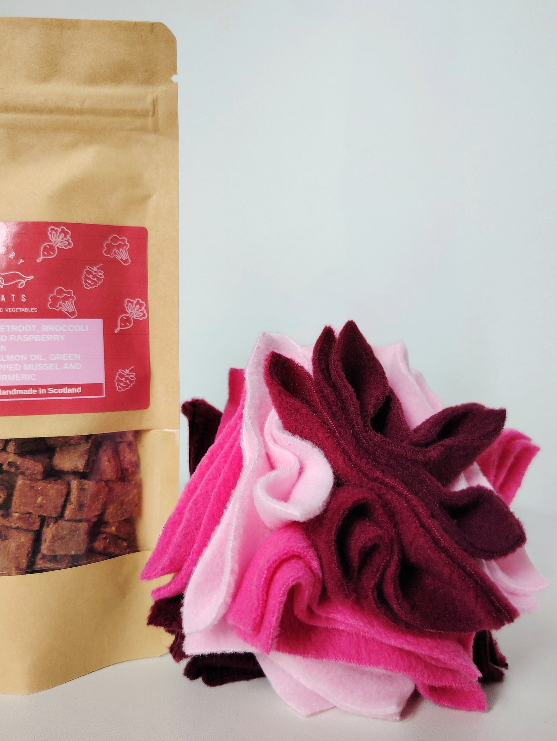 Houndberry dog treats with a handmade Scruffle Ball enrichment toy in pink, plum and pastel pink fleece.