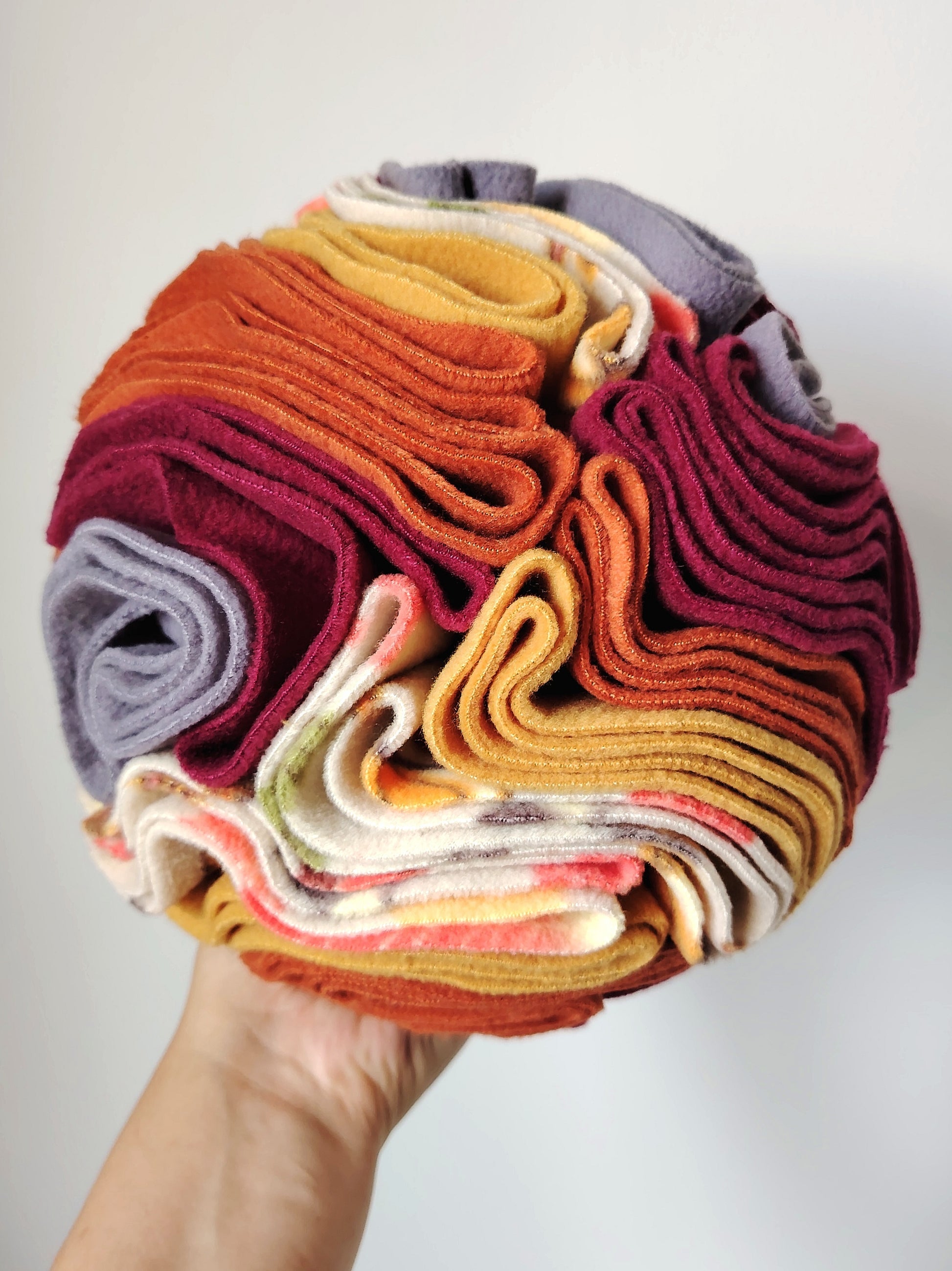 Large Autumn Snuffle Ball for dogs held in one hand to show its size and fleece folds.