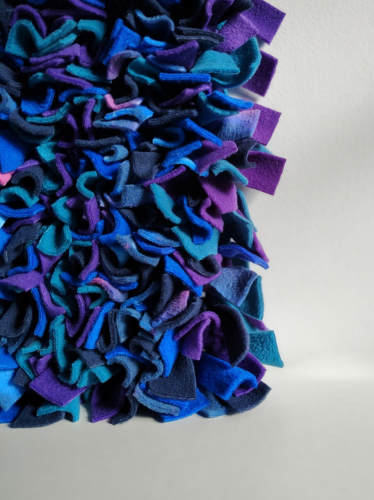 Close-up of a Nova Zeal Night Sky Snuffle Mat showing densely folded navy, royal blue, teal and purple fleece against a light background.