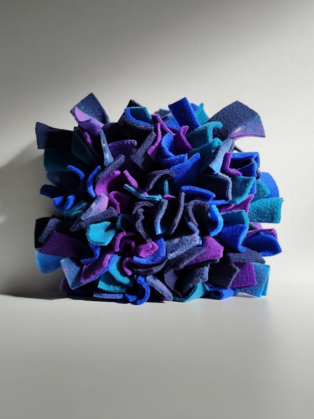 Front view of Nova Zeal's Night Sky Snuffle Mat, showing densely packed folds of navy, royal blue, teal, purple and galaxy-patterned fleece against a light background.