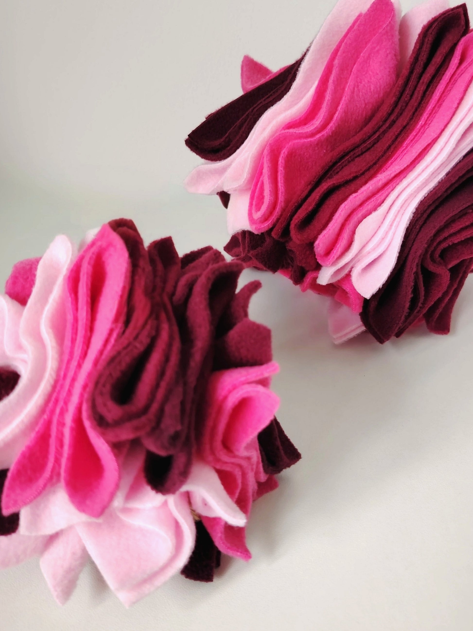 A small and large Nova Zeal Scruffle Balls in layered pink, pastel pink, plum and burgundy fleece.