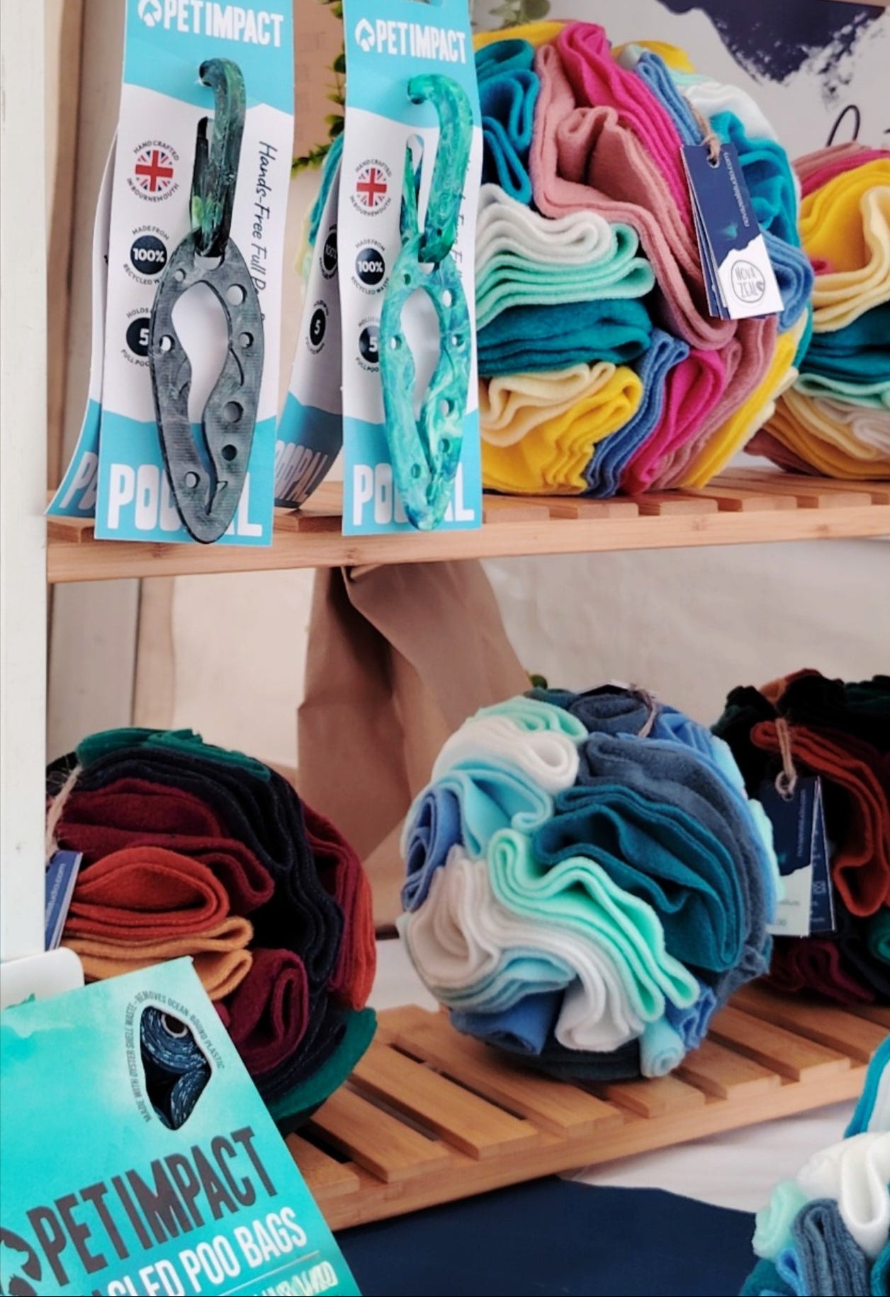 Pet Impact PooPals displayed beside colourful Nova Zeal Snuffle Balls on a wooden retail stand.