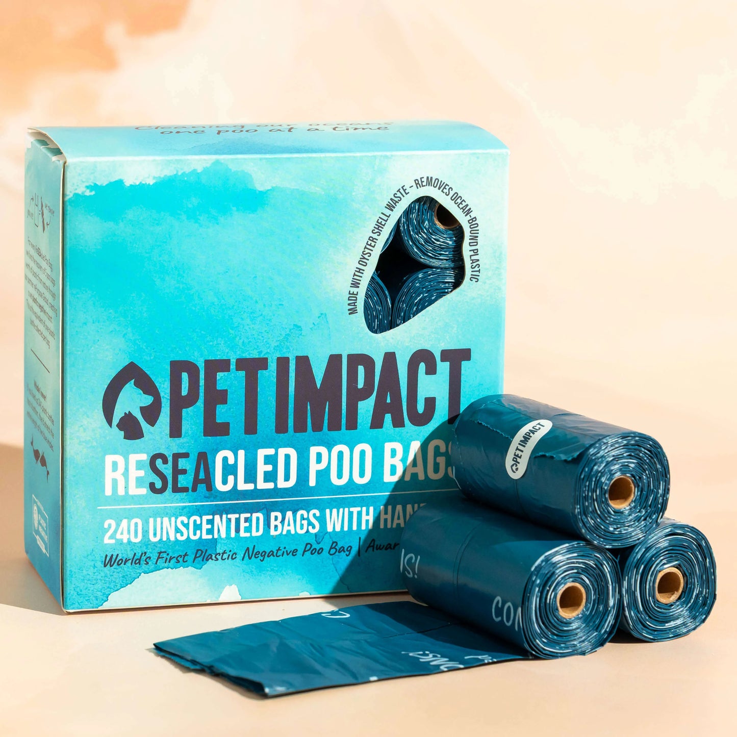 Box of Pet Impact ReSEAcled dog poo bags displayed with several blue rolls and one unfolded bag on a pale background.