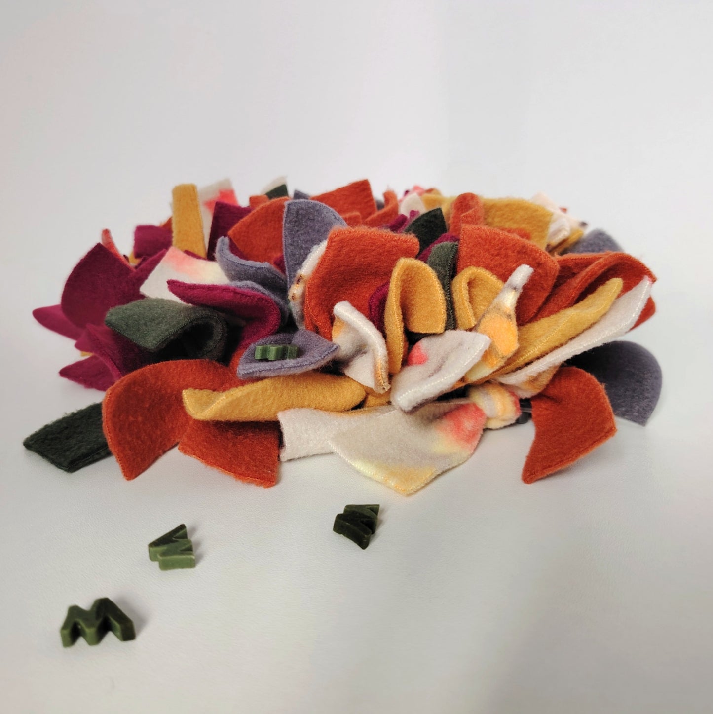 Autumn Snuffle Mat for dogs in rust, mustard, plum, charcoal and patterned autumn fleece with treats hidden between the folds.