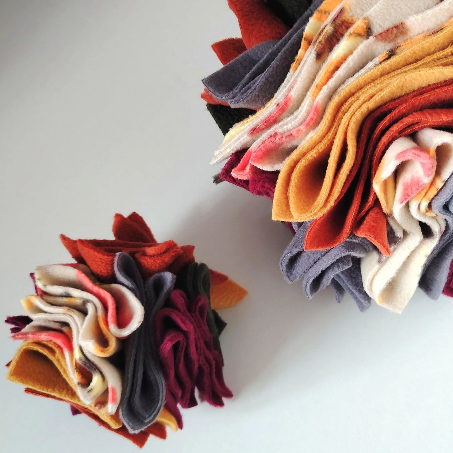 Small and large Nova Zeal Autumn Scruffle Balls showing the difference in size and layered fleece design.
