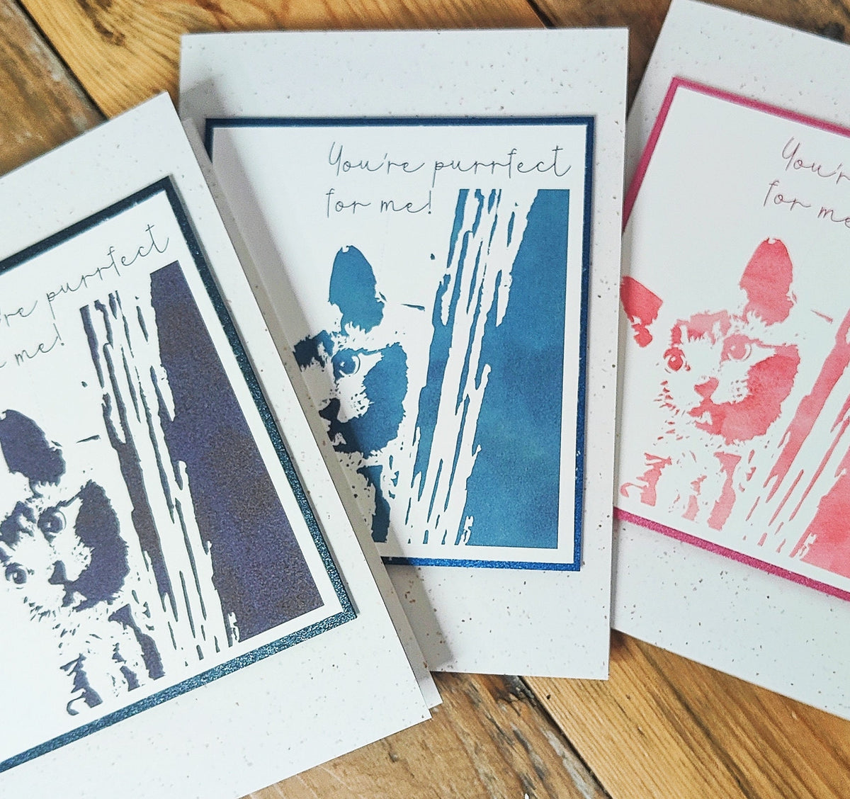 Black, blue and pink "You're purrfect for me" cat cards showing the three available colour options.